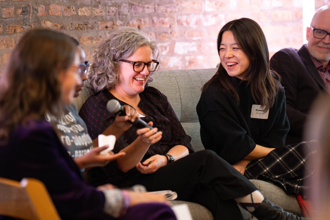 A few individuals sitting on a couch chatting and laughing